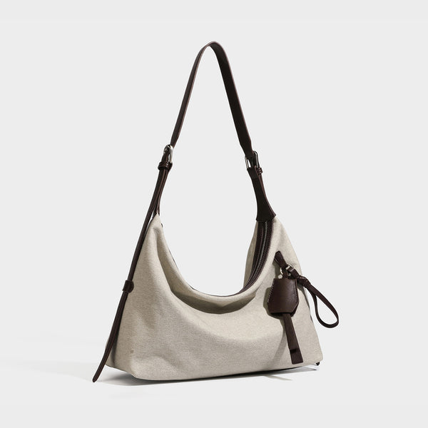 Weich fallende Hobo-Schultertasche aus haferfarbenem Canvas mit dunkelbraunem Besatz in Lederoptik, silberfarbenem Reißverschluss und langem, verstellbarem