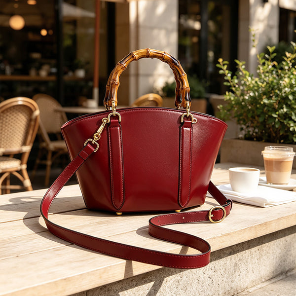 Structured trapezoid handbag with segmented bamboo top handle, smooth leather-look finish, gold-tone hardware, and vertical