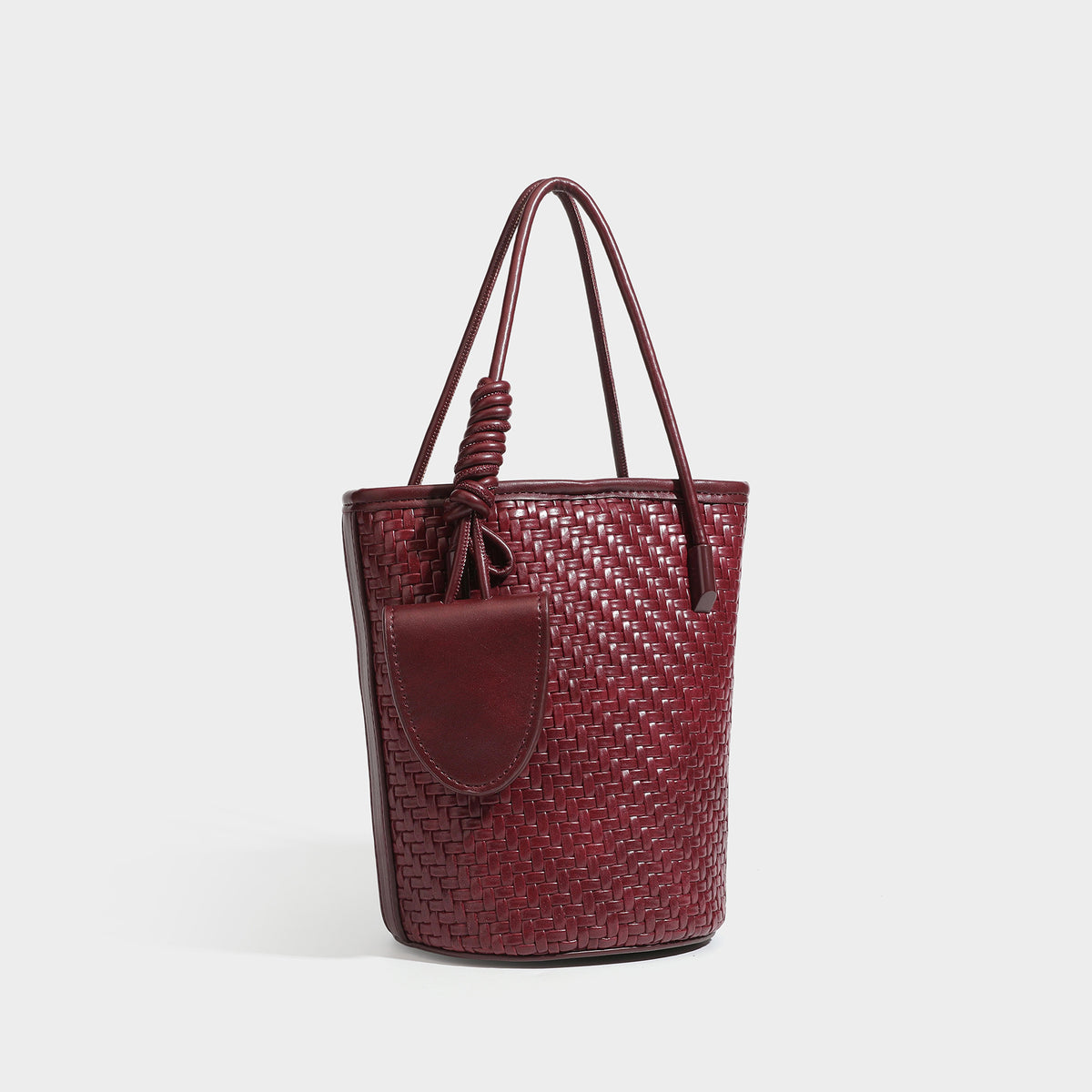 Structured woven-texture leather-look bucket bag in brown with knotted top handles, small front flap pouch, and adjustable