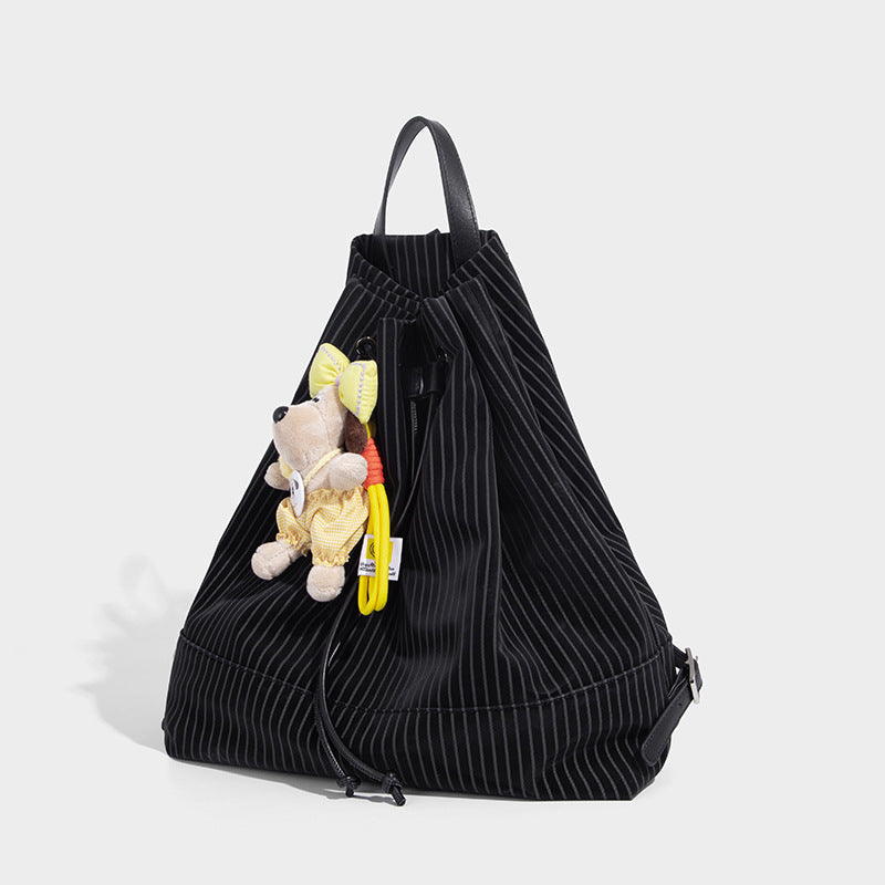 Black pinstripe convertible backpack handbag with drawstring closure, leather-look top handle, and matte hardware, detail