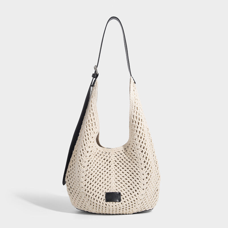 Cream openwork crochet hobo bag with black leather-look strap and trim patch accent, slouchy teardrop silhouette, front view