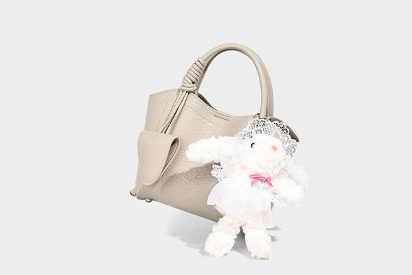 Structured mini tote bag in pebbled leather-look finish with knotted top handles, front flap pocket, and detachable shoulder