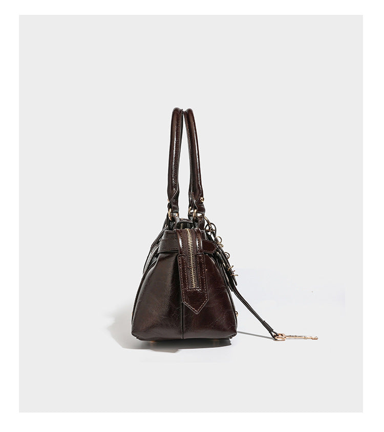 Glossy dark brown structured Boston satchel with heart-shaped lock charm, star pendant, rivet studs, multi-strap front panel