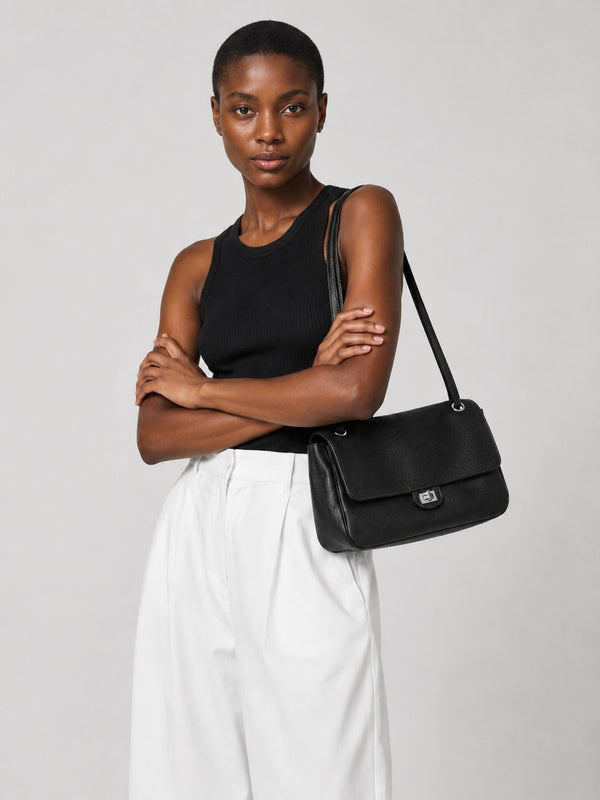 Structured black flap shoulder bag with pebbled texture, silver-tone turn-lock closure, and adjustable single shoulder strap
