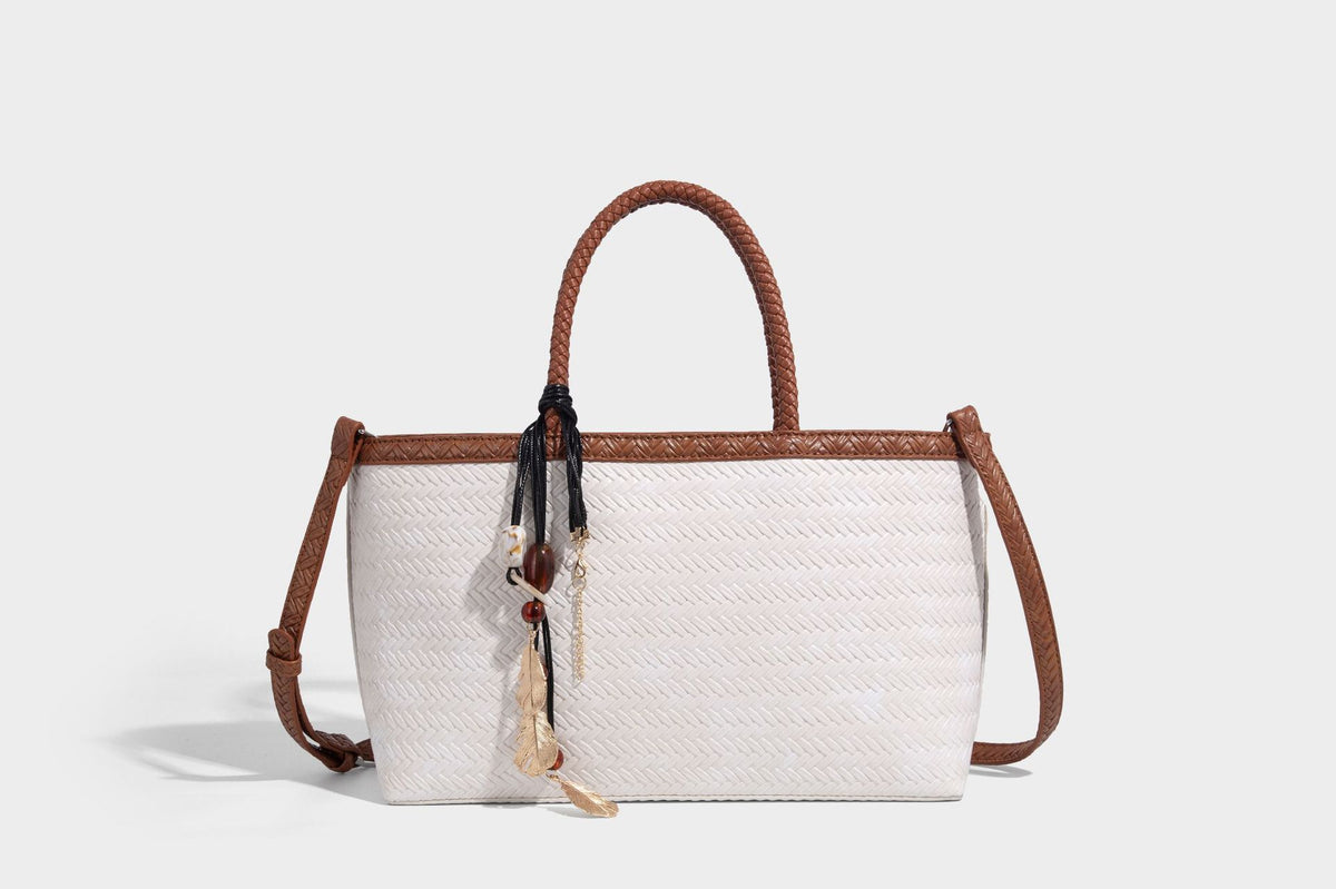 Structured woven-texture tote bag with brown braided top handles, decorative tassel charm, and detachable shoulder strap