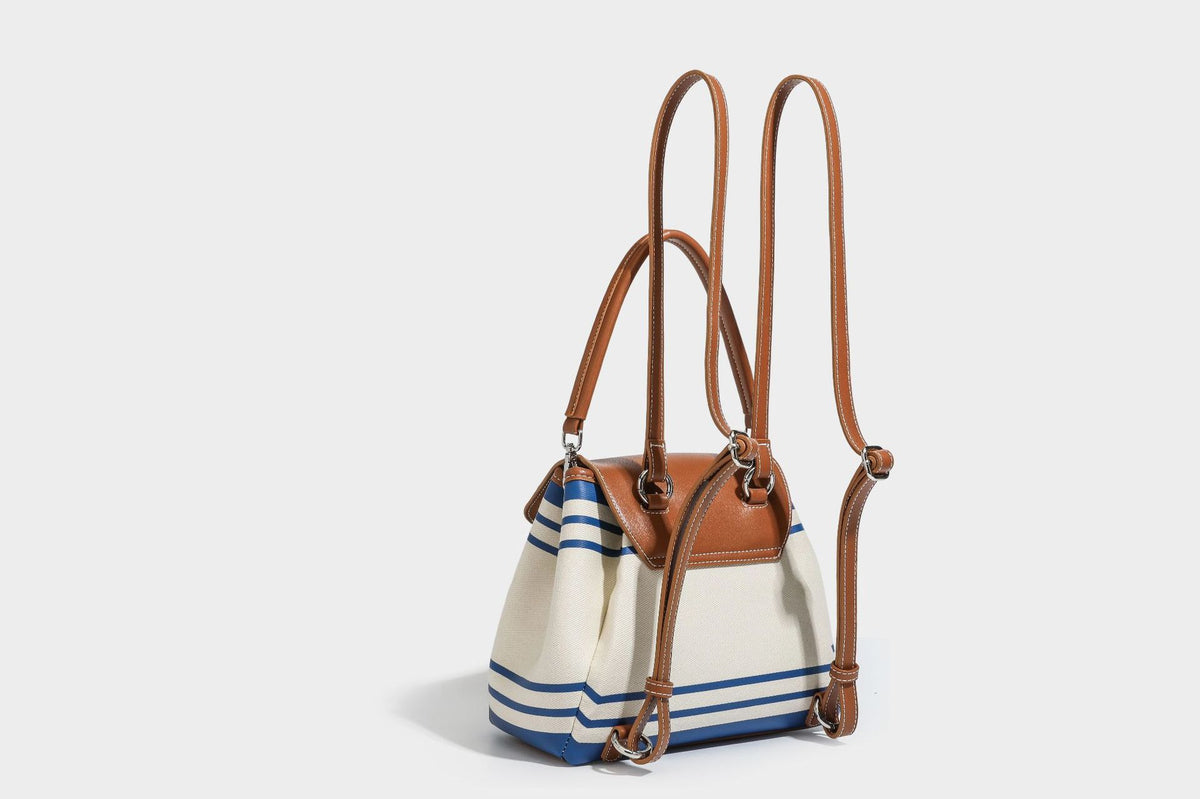 Cream canvas bucket bag with blue horizontal stripes, tan leather-look flap and trim, drawstring closure, silver-tone, detail