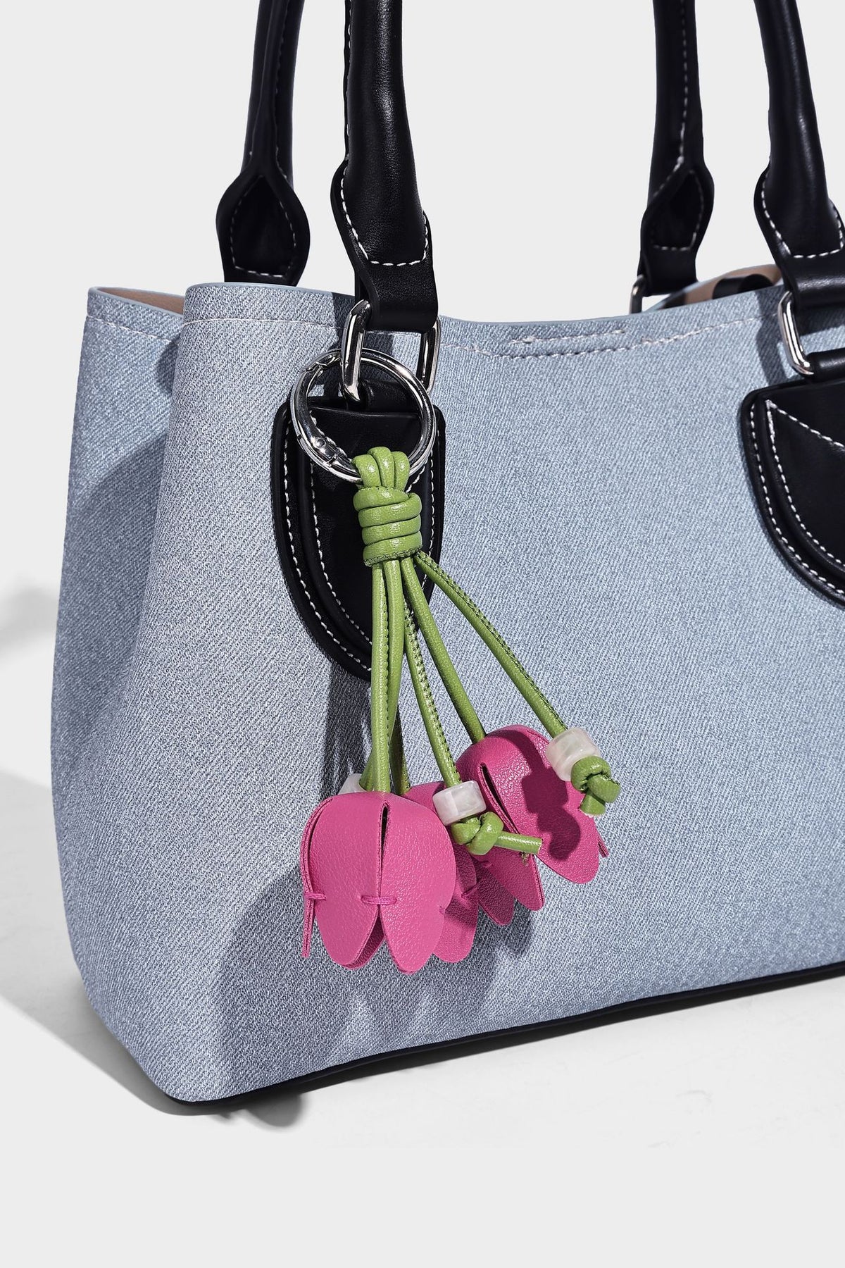 Structured light-blue denim-look tote bag with black leather-look handles, white contrast stitching, silver-tone hardware