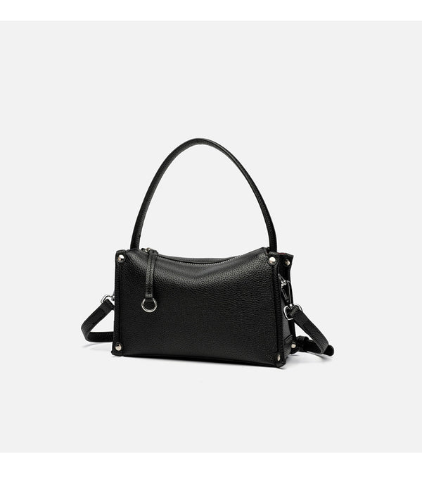 Small structured pebbled-finish convertible bag with silver corner studs, zip top, and detachable shoulder strap, detail view