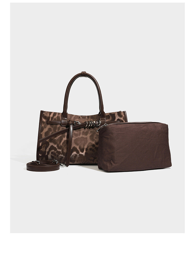 Structured leopard-print tote bag with glossy satin-like finish, dual rounded top handles, silver buckle-and-ring front