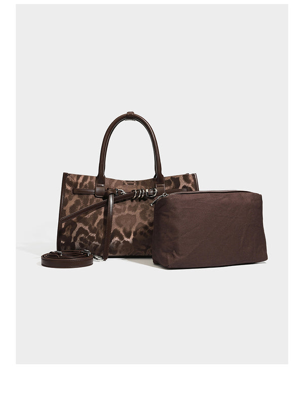 Structured leopard-print tote bag with glossy satin-like finish, dual rounded top handles, silver buckle-and-ring front