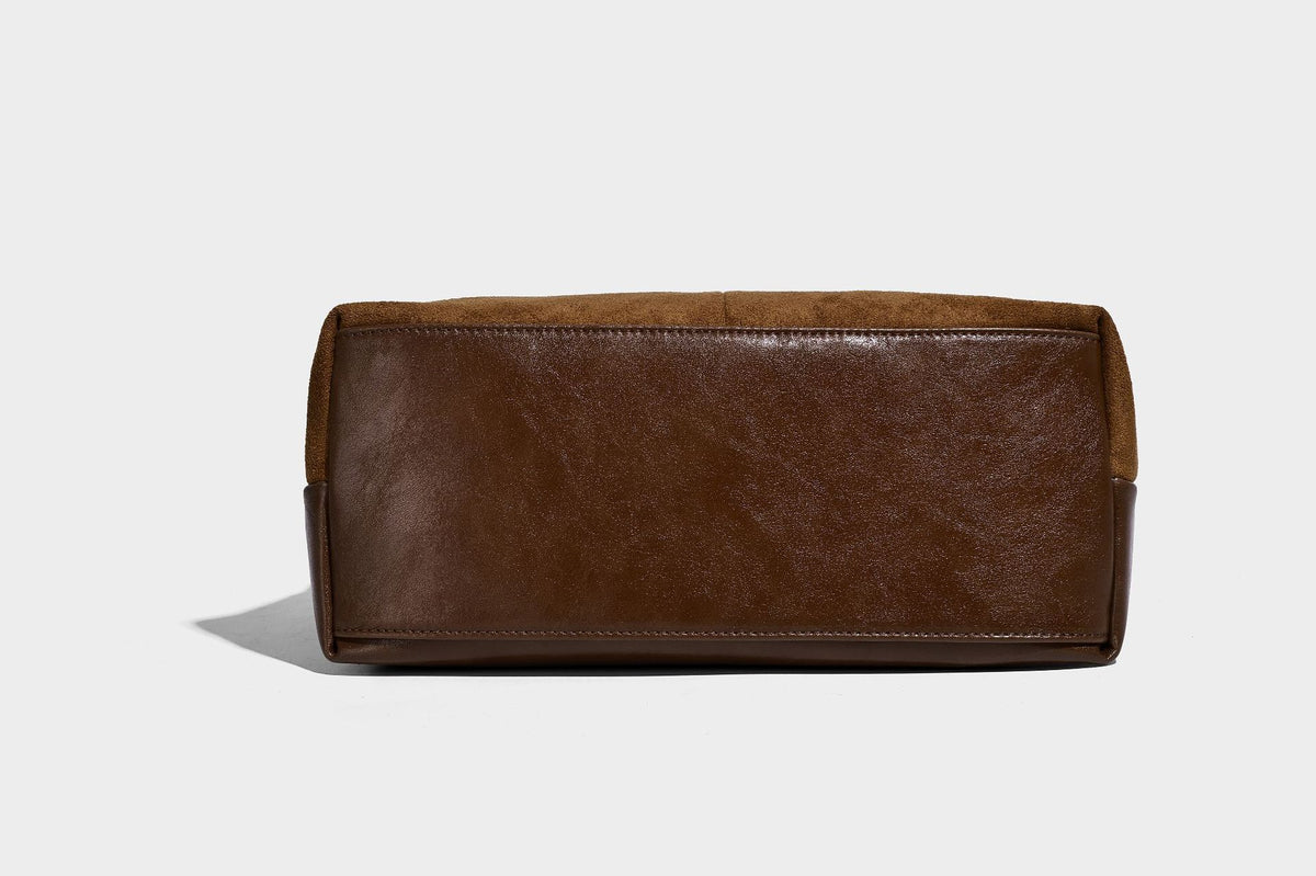 Kompakte Boston-Schultertasche in warmem Braun in Wildlederoptik mit glattem dunkelbraunem Besatz, übergroßen goldfarbenen Ringelementen und Reißverschluss oben