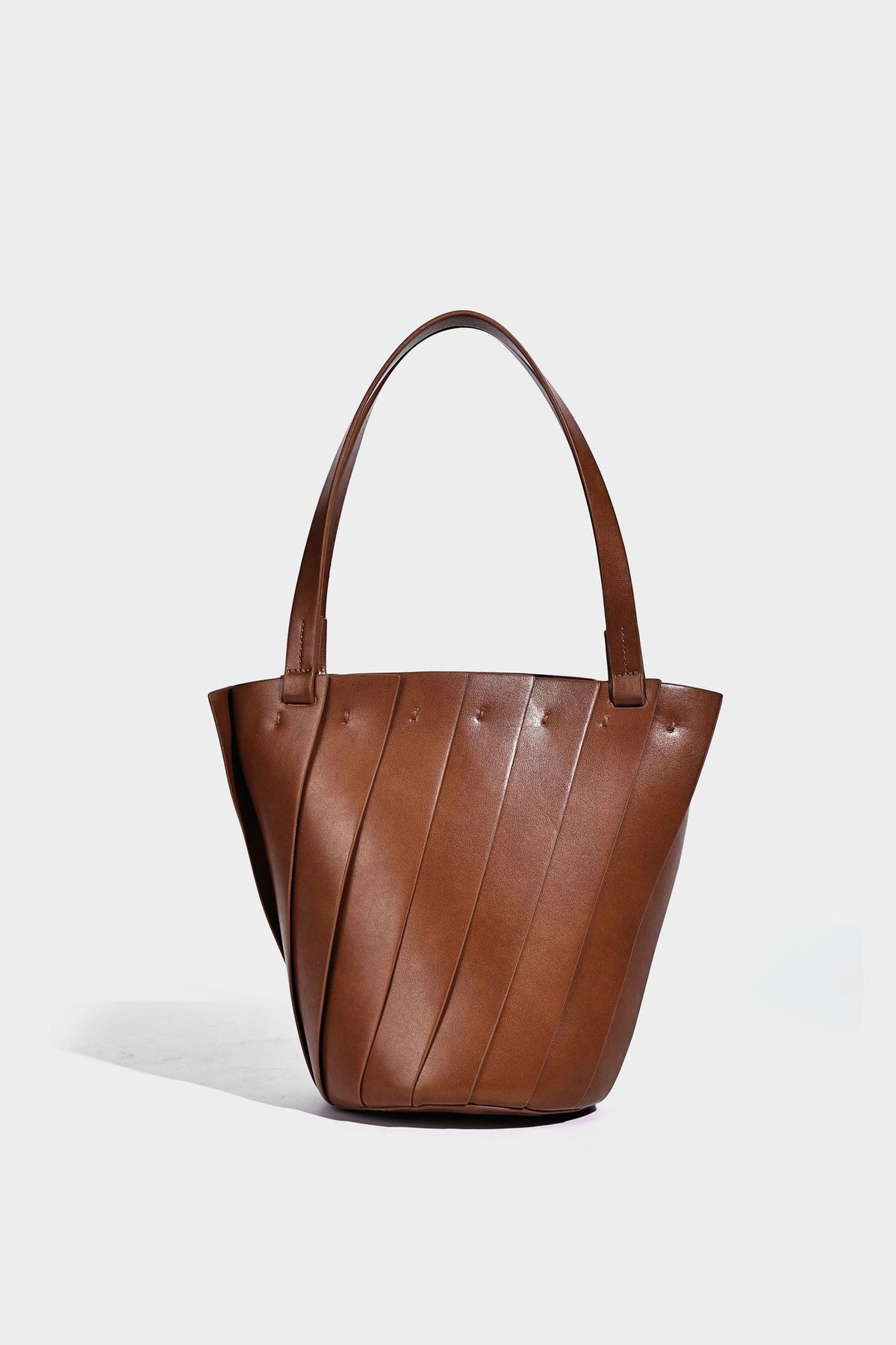 Structured bucket tote bag with vertical panel exterior, dual top handles, and detachable shoulder strap in tan leather-look