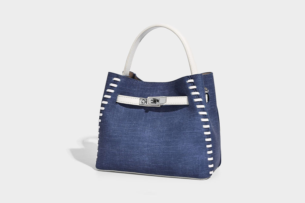 Formstabile Beuteltasche aus Denim mit weißem Zierstich-Besatz, silberfarbenem Drehverschluss, kurzen Henkeln und einem langen verstellbaren
