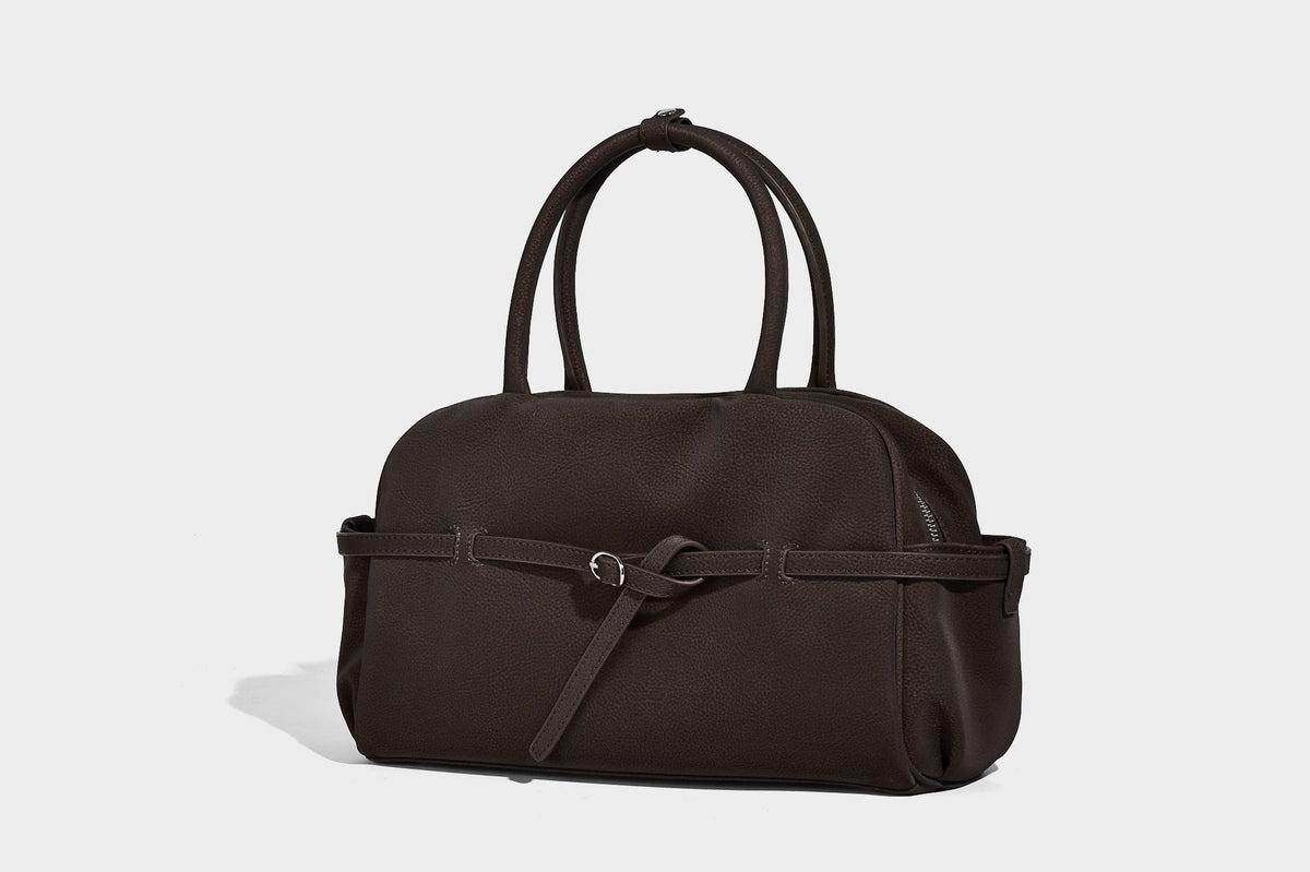 Strukturierte Henkeltasche aus mattem, genarbtem Material mit umlaufendem Riemen und Ringbeschlägen, zwei oberen Tragegriffen und abnehmbarem Crossbody-Riemen