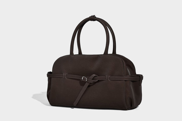 Strukturierte Henkeltasche aus mattem, genarbtem Material mit umlaufendem Riemen und Ringbeschlägen, zwei oberen Tragegriffen und abnehmbarem Crossbody-Riemen