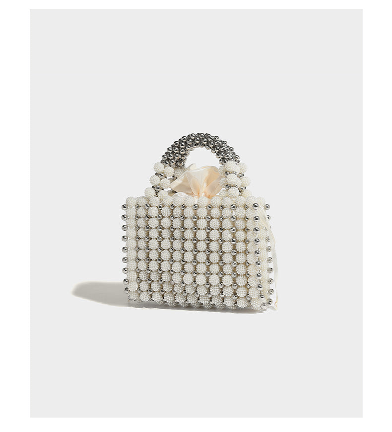 Small boxy pearl-bead mini top-handle bag with silver metallic bead accents, satin floral detail, and long beaded shoulder