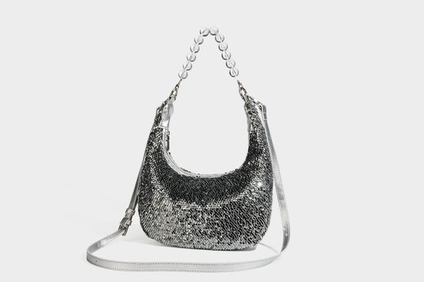 Kleine sichelförmige Schultertasche mit vollständig mit silberfarbenen Pailletten besetzter Außenseite, transparentem Henkel aus kugelförmigen Perlen und Reißverschluss in Silberoptik