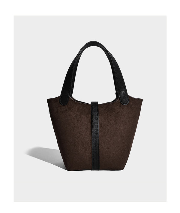 Small structured trapezoid tote bag in matte suede-look finish with black contrast trim, gold-tone front clasp, tassel charm