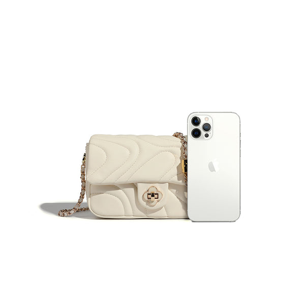 Compact cream quilted flap crossbody bag with wave stitching, gold-tone chain strap, and four-petal turn-lock clasp, detail
