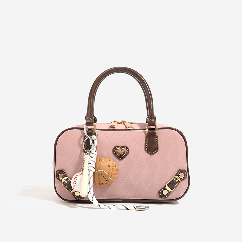 Blush pink quilted bowling barrel bag with dark brown leather-look trim and handles, baseball bat and ball charm, gold-tone