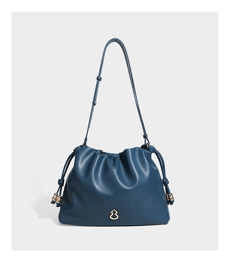 Slouchy ruched drawstring shoulder bag in smooth leather-look finish with gold-tone emblem and slim adjustable strap, detail