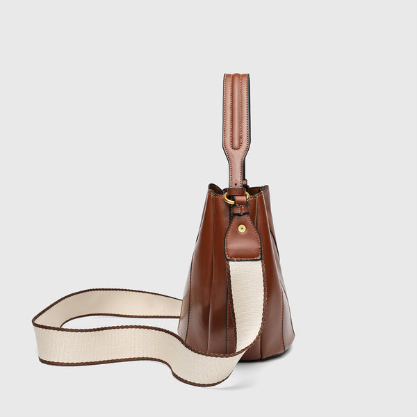 Smooth leather-look paneled bucket bag in brown with wide woven shoulder strap, gold-tone ring hardware, and detachable zip