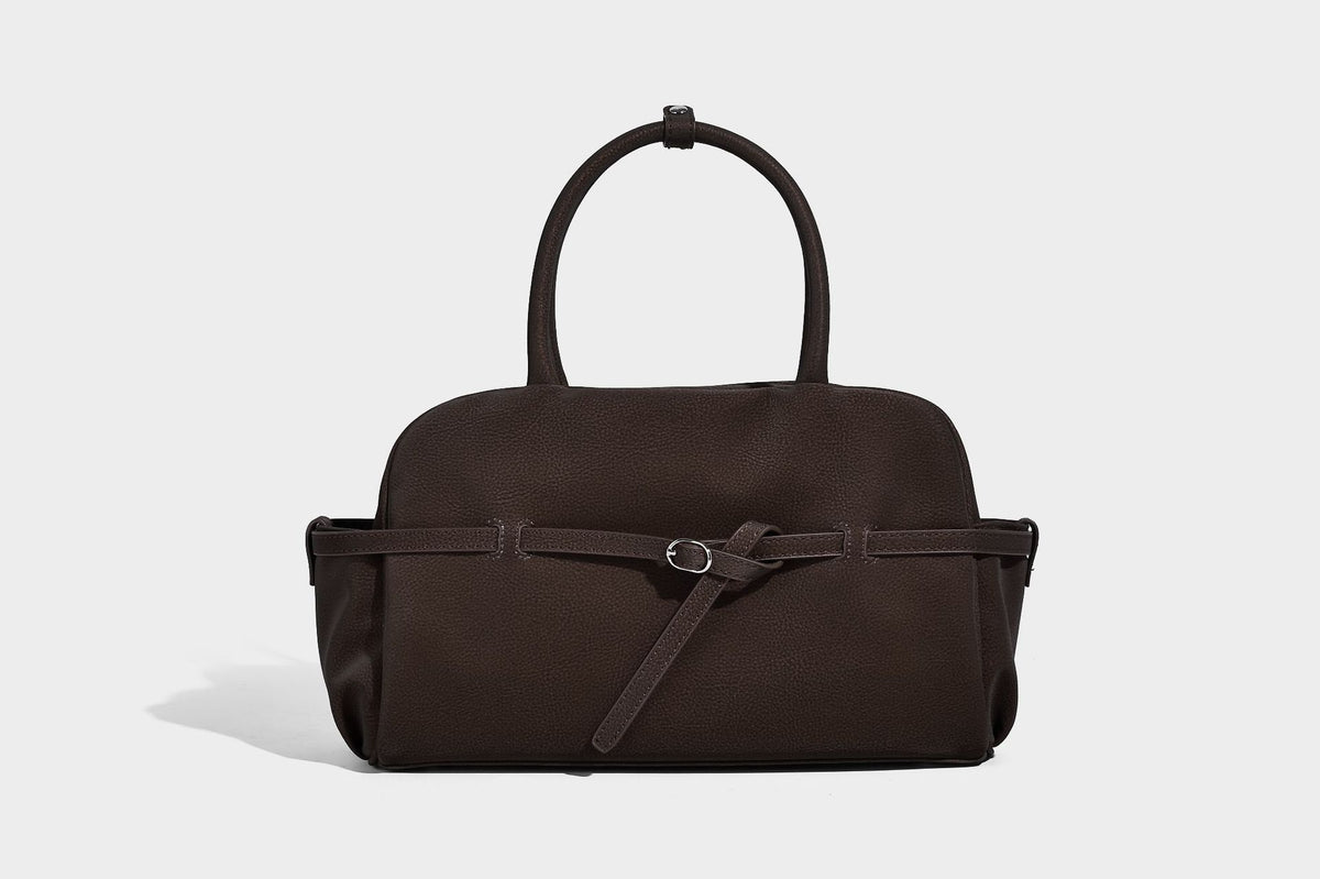 Strukturierte Henkeltasche aus mattem, genarbtem Material mit umlaufendem Riemen und Ringbeschlägen, zwei oberen Tragegriffen und abnehmbarem Crossbody-Riemen