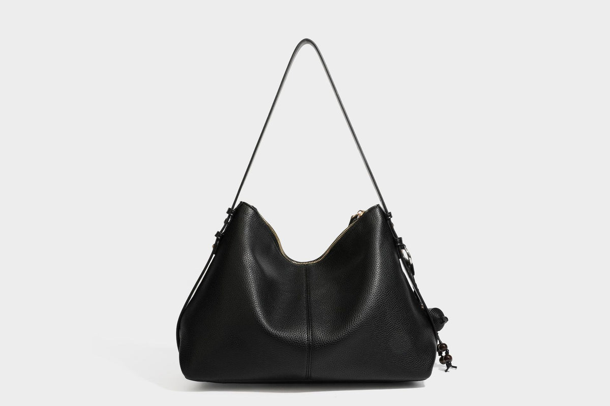 Slouchy hobo shoulder bag with pebbled leather-look finish, zip-top closure, gold-tone hardware, and hanging bead charm