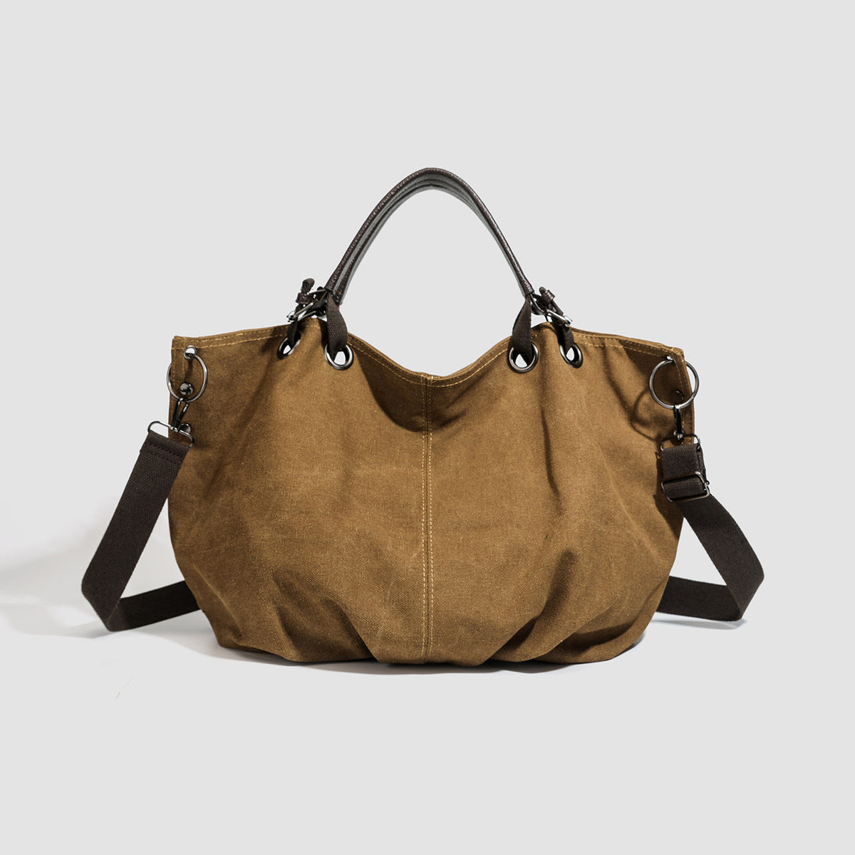 Slouchy matte canvas tote bag with dark dual top handles, metal grommet hardware, and detachable long shoulder strap, detail