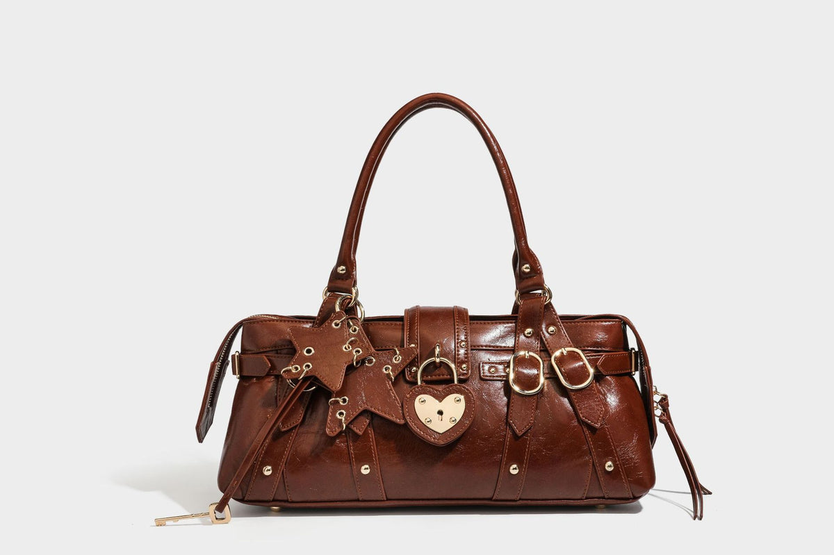 Glossy dark brown structured Boston satchel with heart-shaped lock charm, star pendant, rivet studs, multi-strap front panel