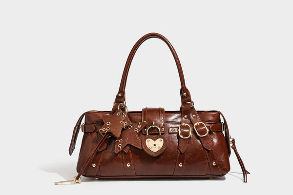 Glossy dark brown structured Boston satchel with heart-shaped lock charm, star pendant, rivet studs, multi-strap front panel