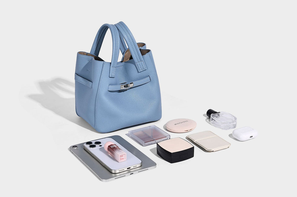 Small structured pebbled bucket tote bag with dual top handles, silver turn-lock front pocket, and detachable shoulder strap