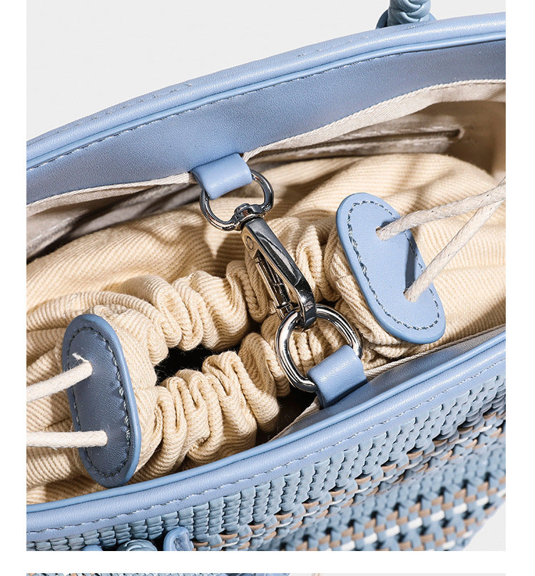 Light blue open-weave woven bucket tote bag with long braided shoulder straps, drawstring side ties, and attached mini pouch