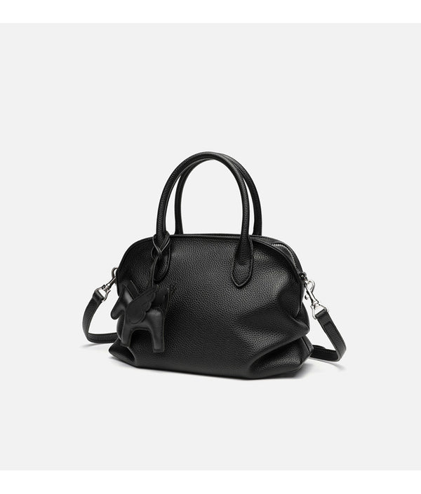 Rounded dome shell handbag in pebbled leather-look finish with twin top handles, zip closure, decorative horse charm, and