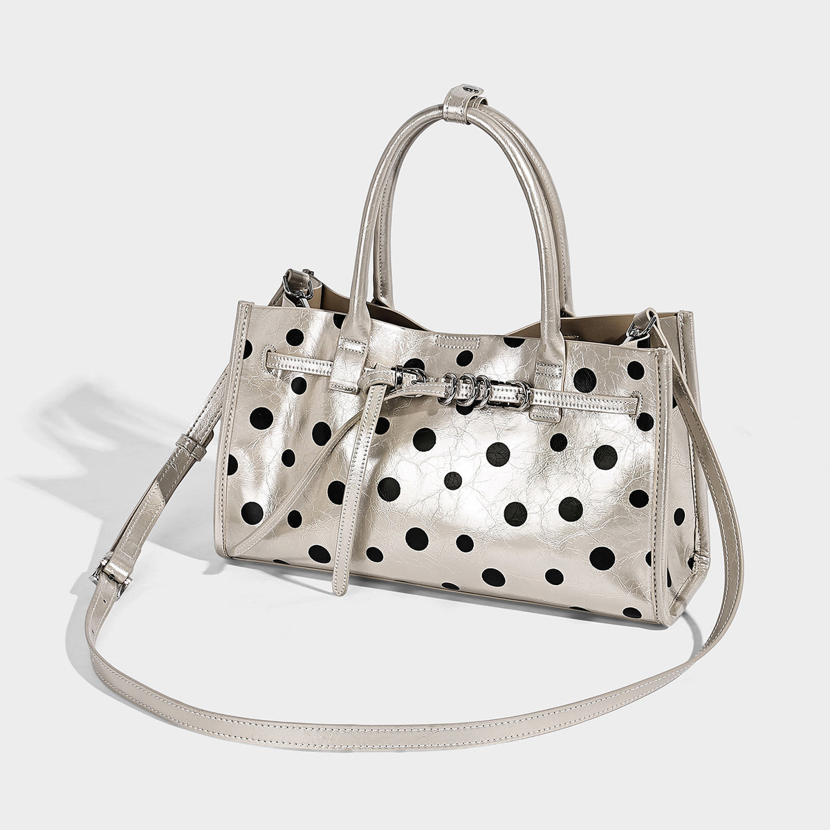 Structured glossy polka-dot tote bag with double top handles and front buckle hardware, detail view 2