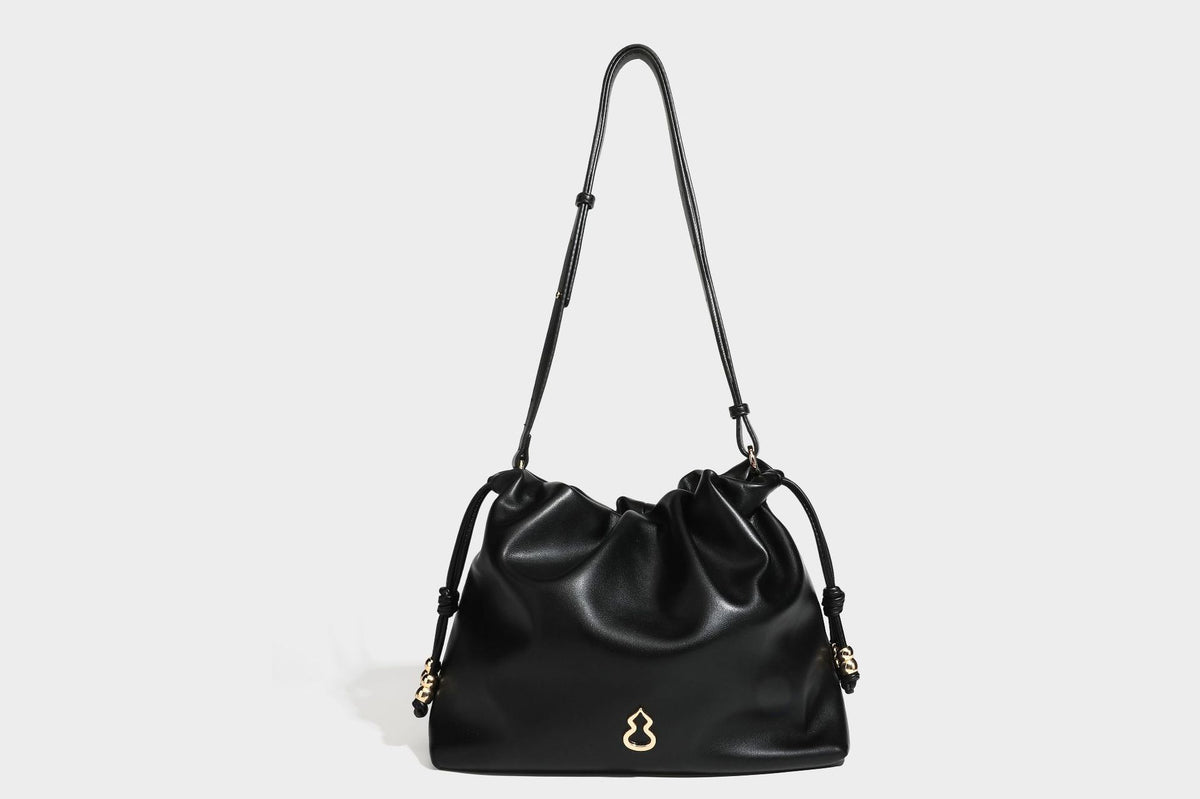 Slouchy ruched drawstring shoulder bag in smooth leather-look finish with gold-tone emblem and slim adjustable strap, detail