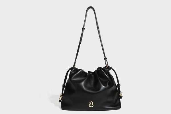 Slouchy ruched drawstring shoulder bag in smooth leather-look finish with gold-tone emblem and slim adjustable strap, detail
