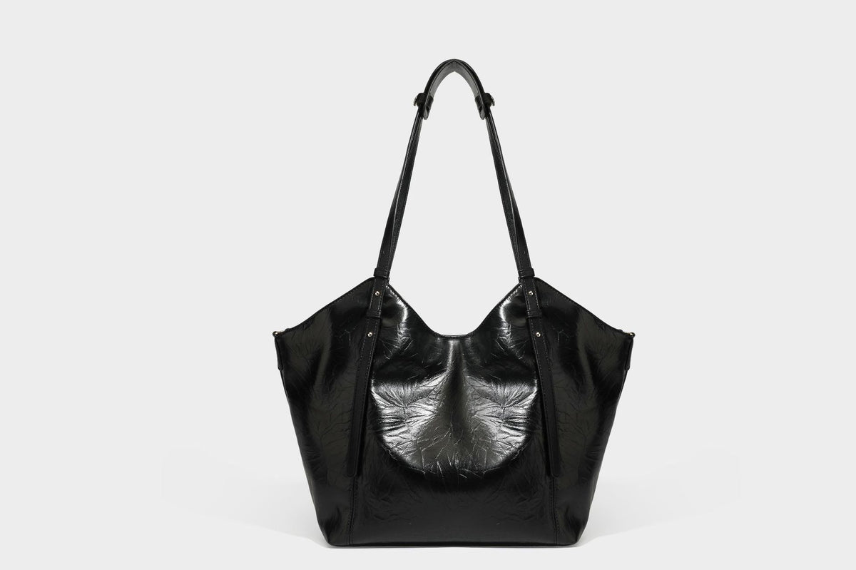 Große, glänzende Tote-Bag aus schwarzem Lederimitat mit geknitterter Optik, lässig fallender Trapezsilhouette, zwei Schulterriemen und goldfarbenen