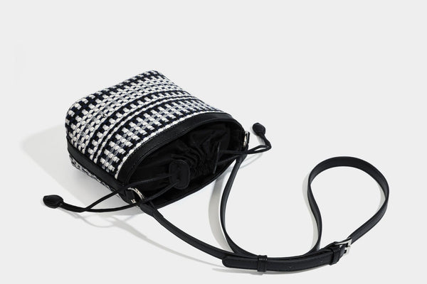 Small structured woven checker bucket bag with braided top handle, drawstring closure, and silver-tone hardware in black