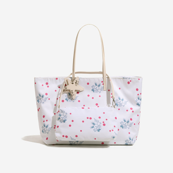 Large reversible floral print tote bag with slim shoulder straps, star charm hardware, and matching zip pouch, detail view 7