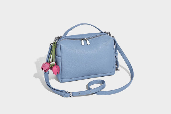 Kleine strukturierte Crossbody-Tasche mit Tragegriff aus genarbtem Material, Reißverschluss, silberfarbenen Beschlägen und optionalem Quastenanhänger