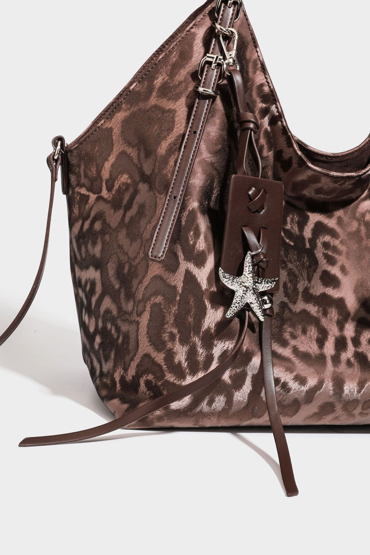 Große, glänzende Hobo-Schultertasche mit Leopardenprint, abnehmbarem Reißverschlusstäschchen und silberfarbenem Seestern-Anhänger, Detailansicht