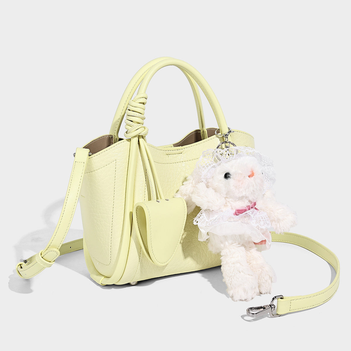 Structured mini tote bag in pebbled leather-look finish with knotted top handles, front flap pocket, and detachable shoulder