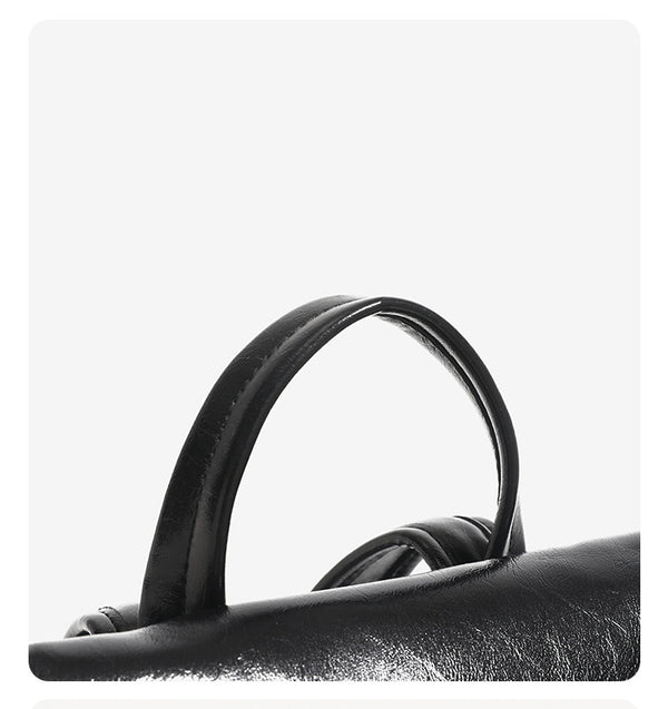 Structured glossy leather-look flap backpack handbag with dual buckle closures, top handle, and silver-tone hardware, detail
