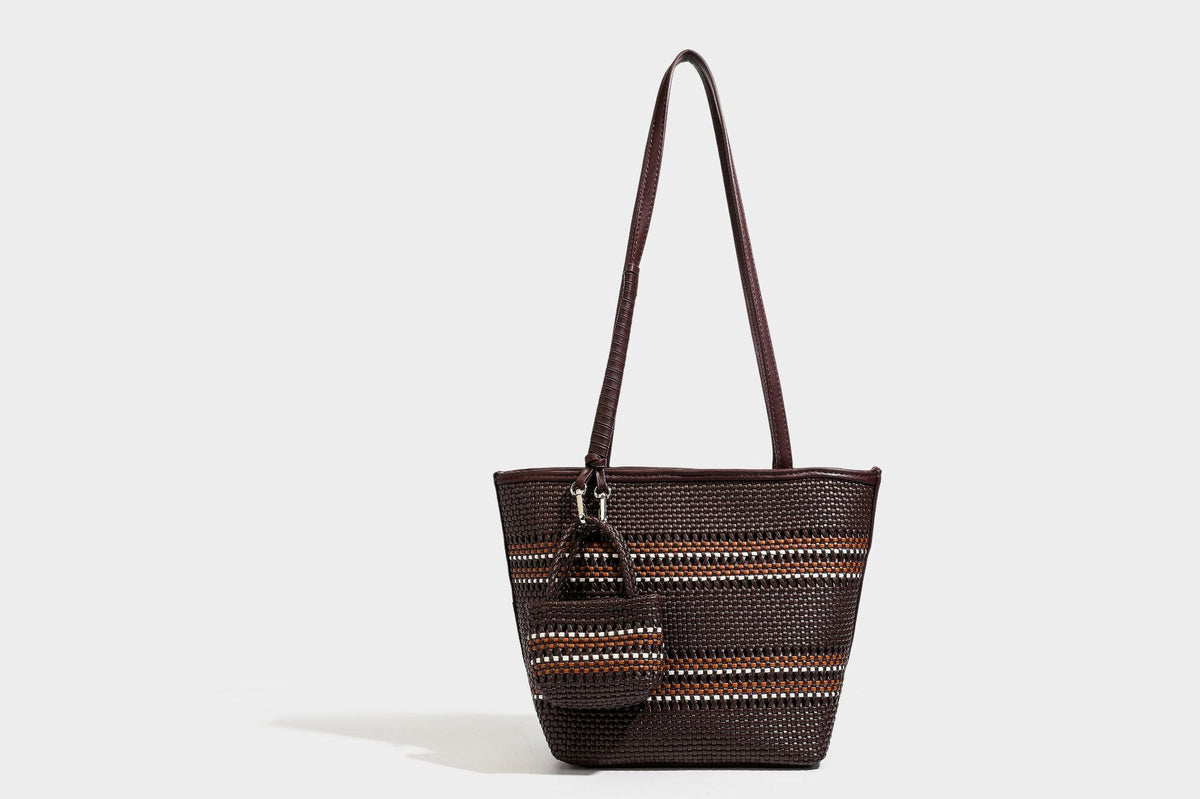 Large structured woven tote bag with striped basket-weave finish, long shoulder straps, and detachable mini pouch charm