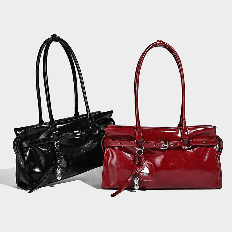 Structured rectangular glossy tote shoulder bag with belt buckle front strap and dangling charm hardware, detail view 2