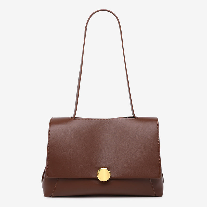 Structured flap shoulder bag with round gold-tone clasp and long flat strap in smooth matte leather-look finish, detail view