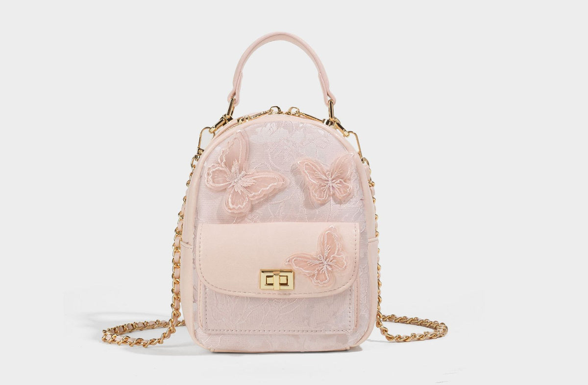 Structured mini backpack handbag with butterfly embroidery, gold-tone chain strap, and turn-lock front flap pocket, detail