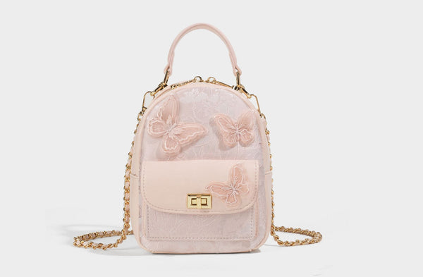 Structured mini backpack handbag with butterfly embroidery, gold-tone chain strap, and turn-lock front flap pocket, detail