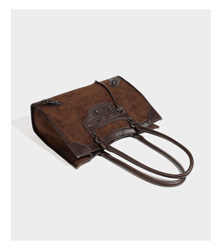 Large structured tote bag with matte suede-like body, smooth leather-look trim, front zip pocket, stud hardware, and